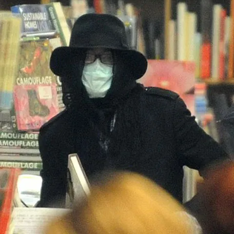 Michael Jackson a fost surprins la cumpărături în pijamale, cu masca chirurgicală pe faţă şi ascunzându-se sub o umbrelă 