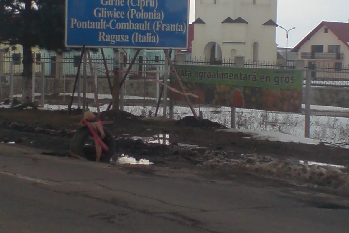 Groapă în astfalt semnalizată cu o anvelopă şi o sticlă de bere