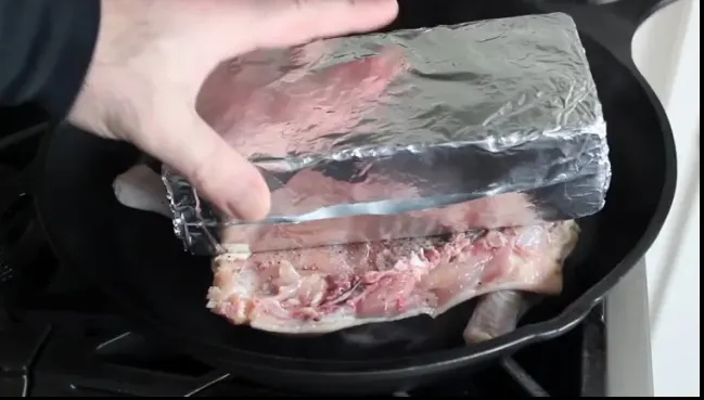 A învelit o cărămidă în folie de aluminiu și a pus-o peste puiul din tigaie. Motivul? E genial!