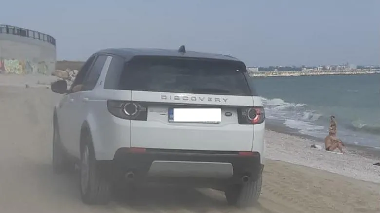 Șmecher cu bolid de lux face slalom printre copii pe plajă