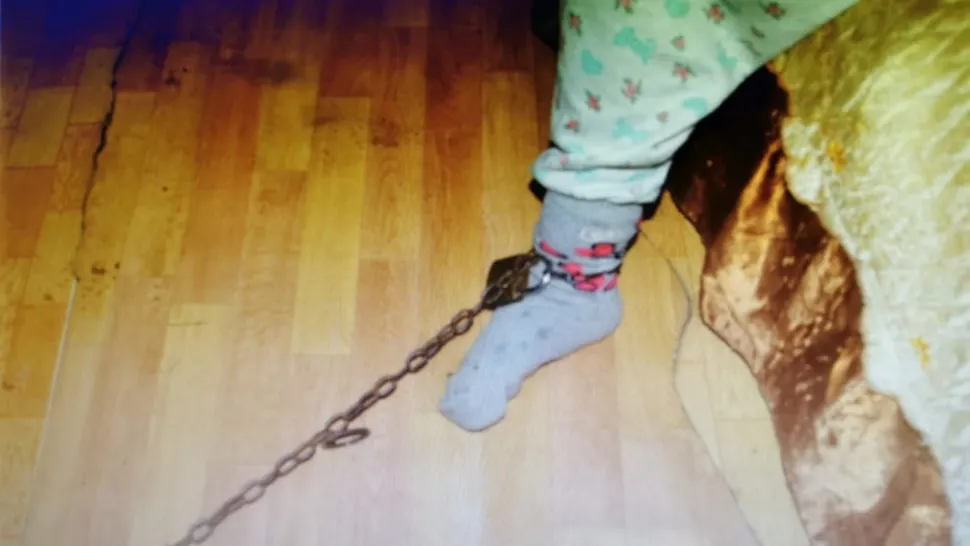 Femeie arestată după ce și-a legat nepoata cu un lanț de piciorul patului