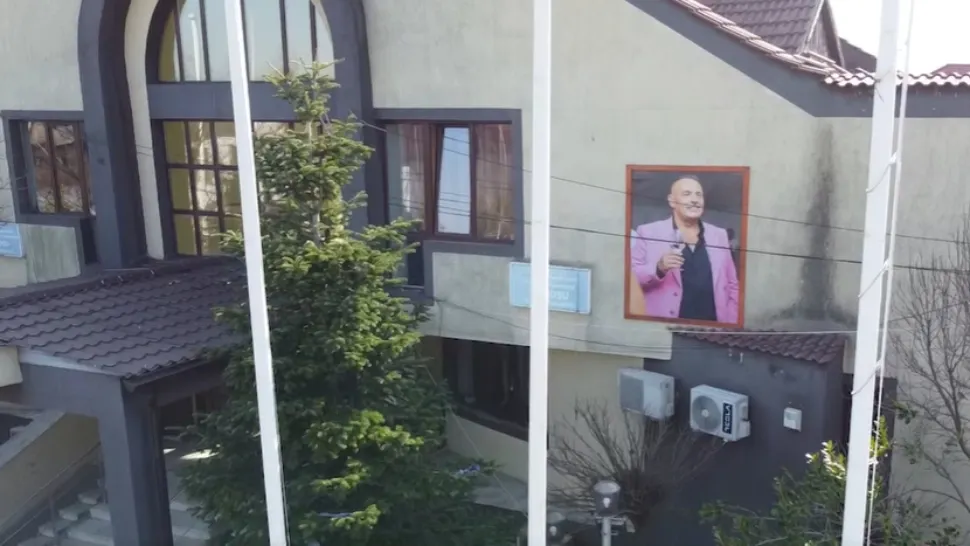 Mega-portretul unui fost primar, în sacou roz și cu paharul în mână, a ajuns să ocupe fațada unei primării din România - VIDEO