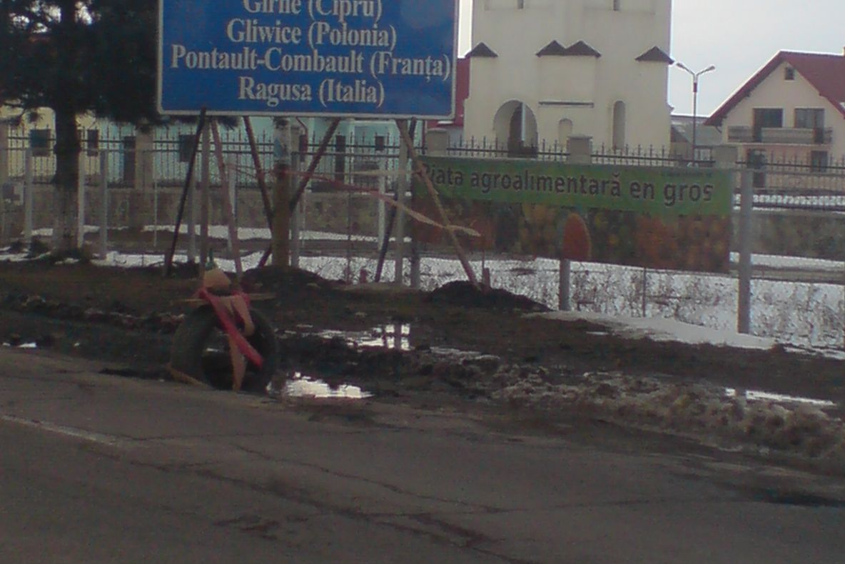 Groapă în astfalt semnalizată cu o anvelopă şi o sticlă de bere