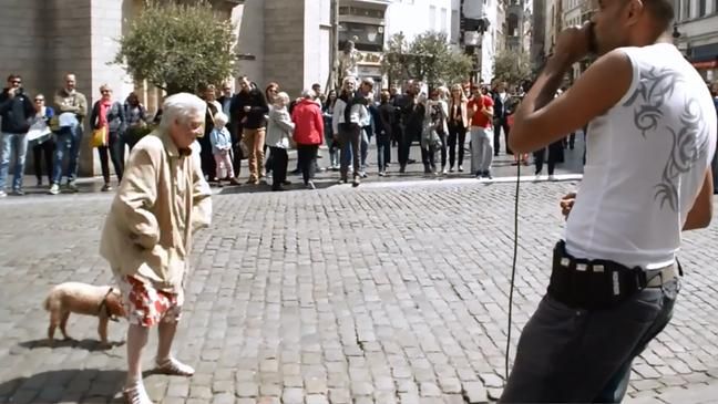 O bătrânică se opreşte în centrul unei pieţe şi face asta. Toată lumea este uimită