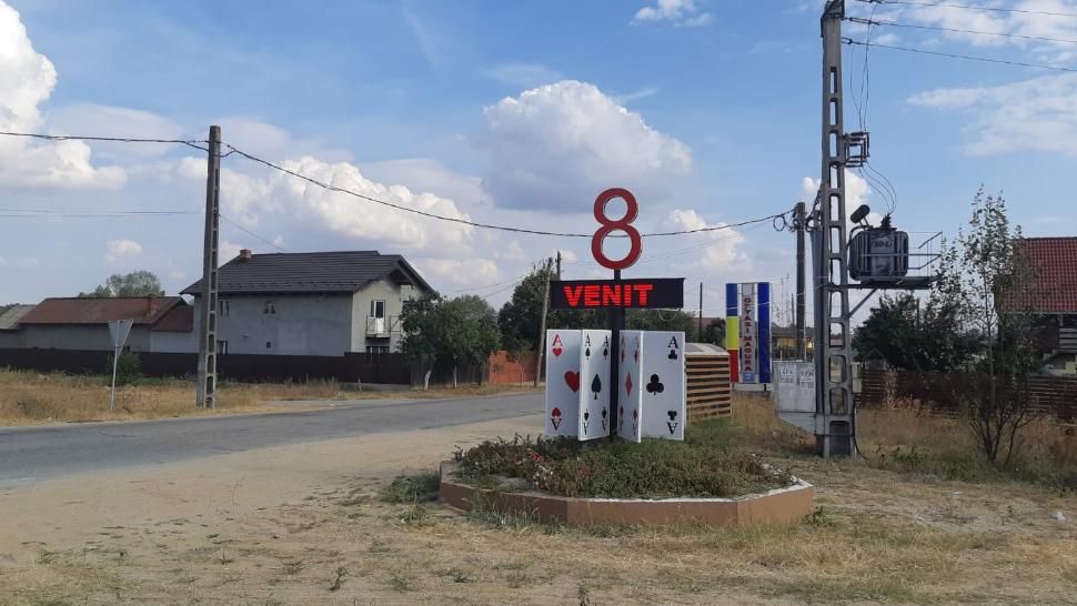 Un totem cu cifra 8 peste opt cărţi de joc imense, la intrarea într-o comună din Olt. Primar: A fost complicat să-l inventez