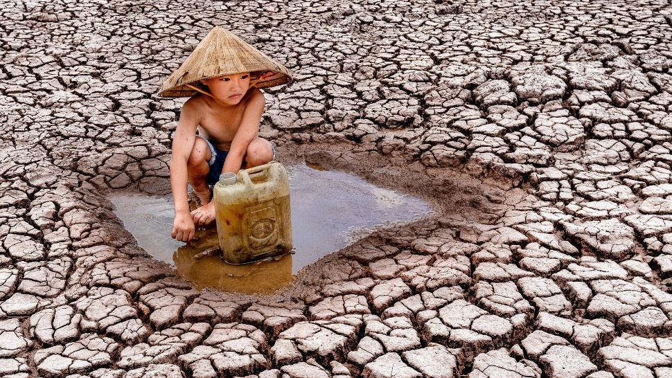 Imagini TULBURĂTOARE cu un copil care adună ultimele picături de apă de pe pământul grav afectat de secetă, în Vietnam