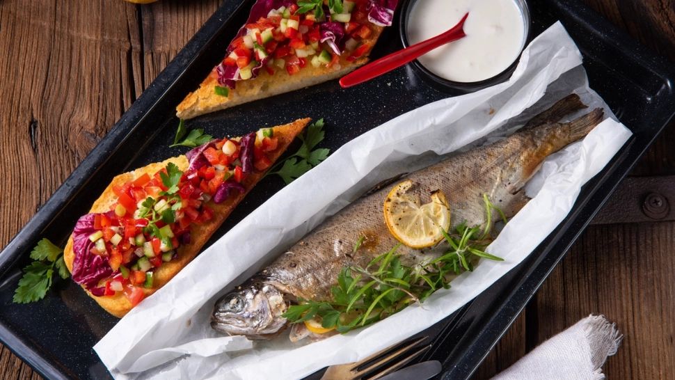 Păstrăv la cuptor, umplut cu ierburi proaspete și felii de lămâie. Ce îl face fraged și suculent