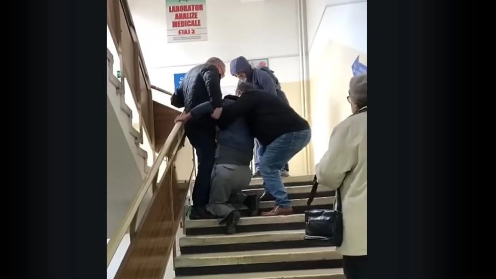 România umilită. Pacient cu probleme la picioare, târât pe scări de două persoane pentru a ajunge la cabinetul medicului VIDEO