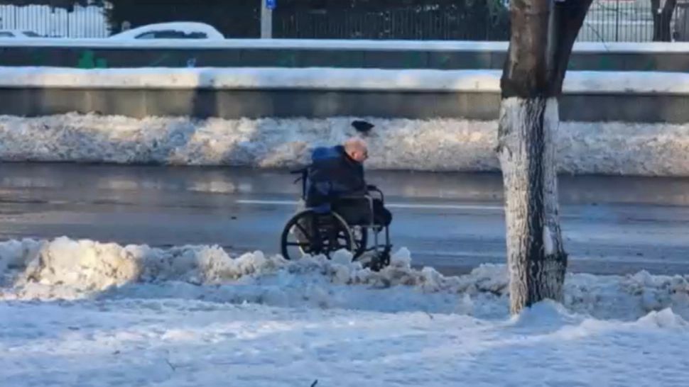 Ireal: Un bărbat în scaun cu rotile, nevoit să circule pe carosabil, printre mașini, din cauza trotuarelor necurățate