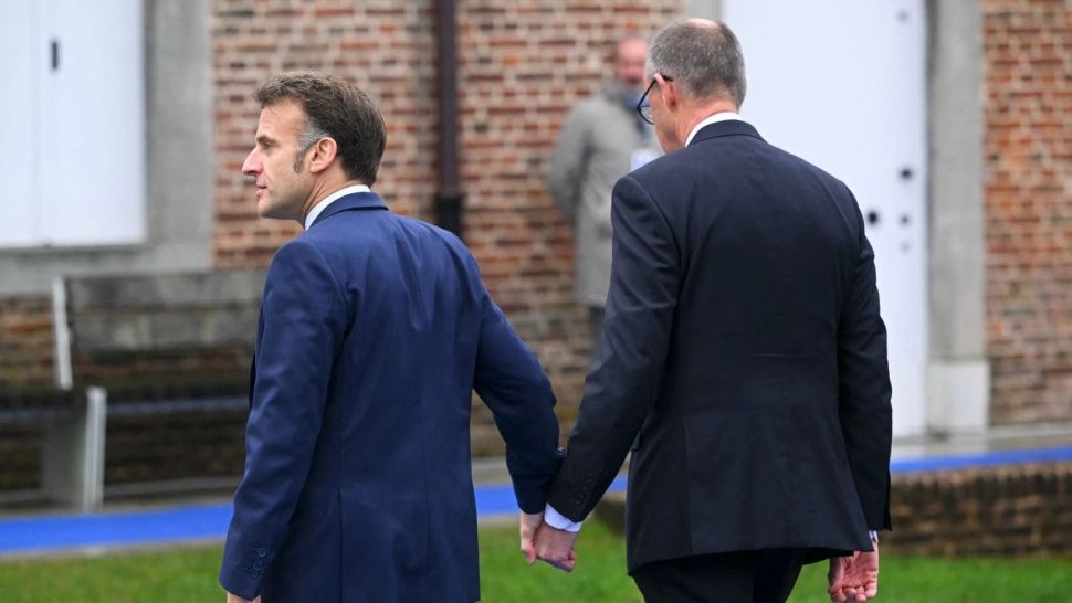 Emmanuel Macron și Friedrich Merz, apariție neașteptată la summitul informal: unitate afișată în ciuda tensiunilor economice. Cei doi s-au ținut strâns de mână