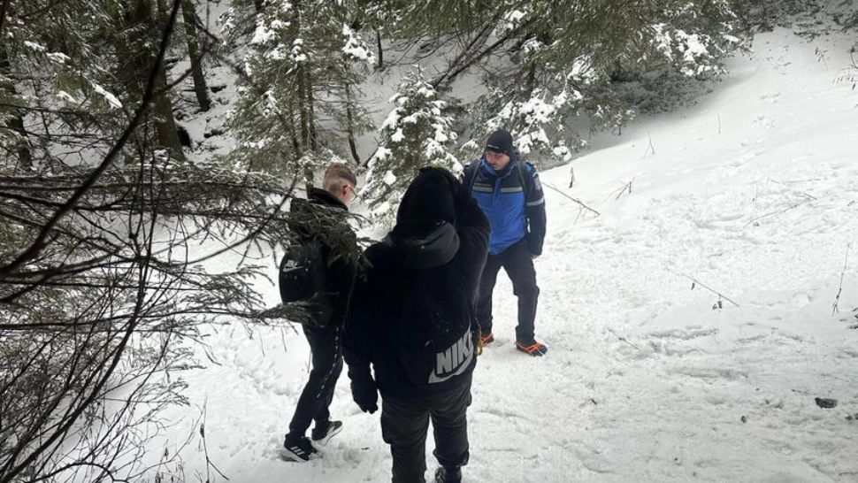 Doi tineri încălțați cu adidași, întorși din drum de jandarmi pe un traseu din Ceahlău