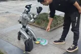 Au apărut roboții cerșetori. Stau în genunchi și le cer trecătorilor să îi ajute să își plătească factura la curent