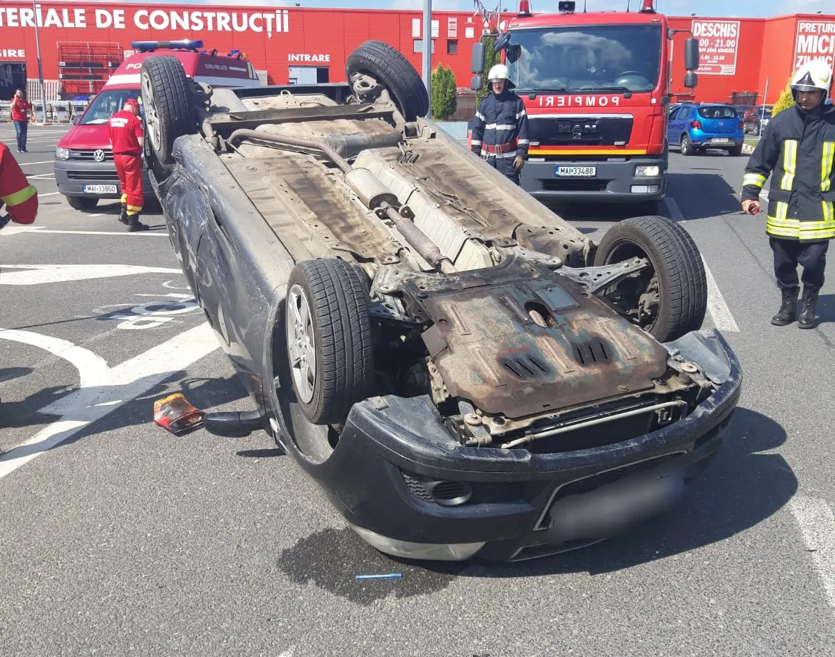 Accident incredibil în parcarea unui supermarket. O mașină, răsturnată