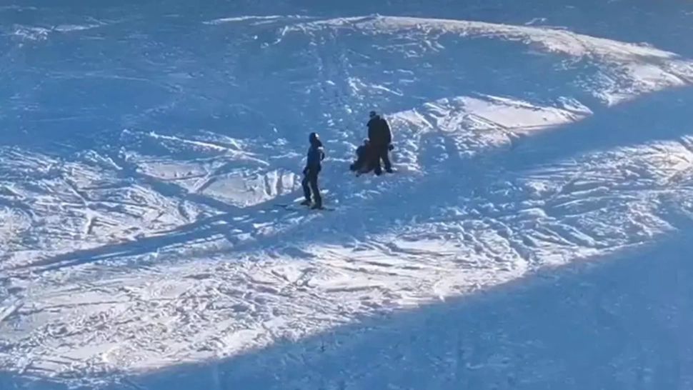 Femeie în fustă pe pârtie, coborâtă de un jandarm montan