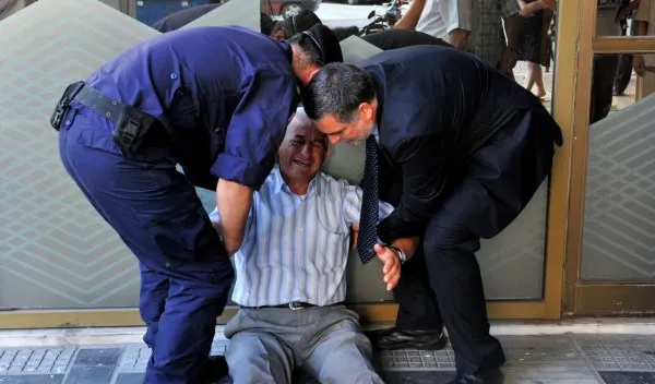 Tragedia greacă în imagini. Fotografia neputinței. Un bătrân plânge, deznădajduit, în fața băncilor