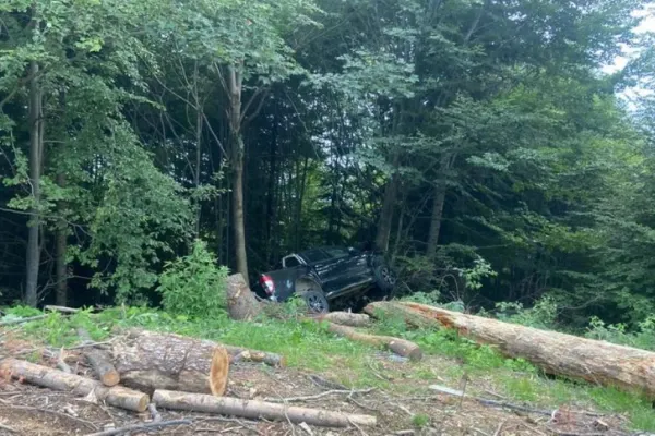 Accident cumplit în Vâlcea: o mașină s-a răsturnat și a rămas agățată de un copac. Victimele sunt o femeie și doi copii