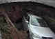 Maşină înghiţită de un crater uriaş surpat în parcare. Ce ascundea groapa şi de ce NU va fi astupată