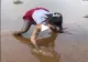 VIDEO – A văzut ceva în apă și s-a băgat în nămol până la gât – Ce a putut scoate, cu mâinile goale, după câteva minute